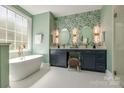 Elegant bathroom featuring double vanity, soaking tub under a large window, and stylish wallpaper at 4340 Sequoia Red Ln, Charlotte, NC 28226