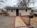 Simple tan home featuring gravel front yard, brick accents, and black mailbox at 1224 Hollywood Ter, Albemarle, NC 28001