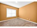 This cozy bedroom has neutral carpeting and a large window with blinds for privacy at 14333 Maclauren Ln, Huntersville, NC 28078