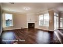 Light-filled living room with hardwood floors, fireplace, and large windows showcasing the outdoor view at 149 Prestwick Way # 39, Mooresville, NC 28115