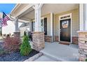 Charming front porch detailing stacked stone columns, a black front door and cozy seating area at 3193 Burnello Ct, Iron Station, NC 28080