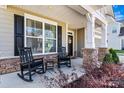 Welcoming front porch with black rocking chairs, stone accents, and stylish shutters at 3193 Burnello Ct, Iron Station, NC 28080