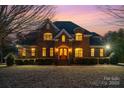 Charming brick home with meticulous landscaping, featuring a welcoming front entrance with illuminated windows at 4421 Windwood Cir, Charlotte, NC 28226