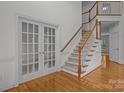 Elegant foyer featuring hardwood floors, staircase with wooden railing, and glass french doors at 561 Keystone Nw Ct, Concord, NC 28027
