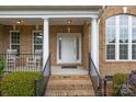 Inviting front porch with classic columns, rocking chairs, and brick stairs with black iron railings at 561 Keystone Nw Ct, Concord, NC 28027