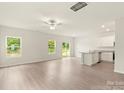 Bright open-plan living area featuring wood floors, a ceiling fan, and an adjacent kitchen area at 102 Lightning Dr, Shelby, NC 28152