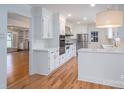 Bright kitchen boasts white cabinets, stainless steel appliances, subway tile backsplash, and hardwood flooring at 104 N Hawthorne St, Mount Holly, NC 28120