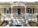 Close-up of the front porch with a teal door, white columns, and decorative hanging flower baskets at 1135 Old Charlotte Rd, Concord, NC 28027