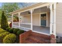 Inviting front porch featuring brick steps, a teal door, and decorative trim at 1135 Old Charlotte Rd, Concord, NC 28027