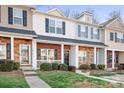 Charming townhouse exterior with brick accents, a small porch, and manicured landscaping at 12417 Mcgrath Dr, Charlotte, NC 28269