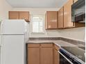 Kitchen features brown cabinets, a microwave, a range, and a white refrigerator near a window at 1606 Eagles Pl # J101, Rock Hill, SC 29732