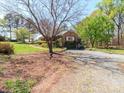 Gravel driveway leads to a brick home with a two-car garage and beautifully landscaped surroundings at 17109 Cabarrus Rd, Midland, NC 28107