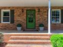 Inviting front entrance features a green door, brick steps, and decorative plants at 17109 Cabarrus Rd, Midland, NC 28107