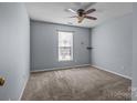 Neutral bedroom showcasing soft carpet, a ceiling fan, and a sunlit window with neutral-toned walls at 228 Grayland Rd, Mooresville, NC 28115