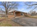 Brick ranch home featuring a covered side porch, level yard and mature trees at 2500 Belshire Dr, Conover, NC 28613