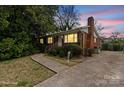 Charming single-story brick home featuring a well-manicured lawn and a concrete driveway at dusk at 2922 Dunlavin Way, Charlotte, NC 28205