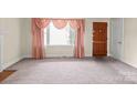 Bright living room featuring a cozy fireplace, large window, and neutral carpet at 2922 Dunlavin Way, Charlotte, NC 28205