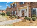 Close-up of a home's front entrance with brick steps, decorative sidelights, and lush landscaping adds curb appeal at 725 Stanhope Ln, Matthews, NC 28105