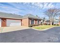 Charming brick home featuring a well-manicured lawn, landscaping, and an attached garage under a partly cloudy sky at 8462 Highland Glen Dr, Charlotte, NC 28269