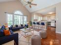 Open-concept living room featuring a vaulted ceiling, large windows, and access to the modern kitchen area at 9307 Harlow Creek Rd, Huntersville, NC 28078