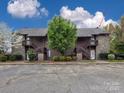 Condo complex with brown siding, stone accents, exterior staircases, and surrounding landscaping at 1022 Mallard Head Ln, Mooresville, NC 28117