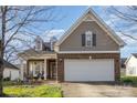 Charming home featuring a brick facade, two-car garage, well-manicured lawn, and covered front porch at 14014 Acorn Creek Ln, Charlotte, NC 28269