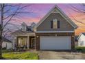 Charming home featuring a brick facade, two-car garage, well-manicured lawn, and covered front porch at sunset at 14014 Acorn Creek Ln, Charlotte, NC 28269