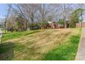 Wide shot of a brick home set atop a gently sloping lawn with mature trees and shrubs adding to its natural beauty at 5536 Seacroft Rd, Charlotte, NC 28210