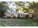 Inviting home exterior with string lights, covered porch, lush greenery and mature trees at 7794 Live Oaks Dr, Denver, NC 28037