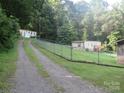 Long gravel driveway leading to multiple mobile homes on a tree covered lot, needs TLC at 1000 Jl Tyson Dr, Gastonia, NC 28056