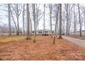 Lawn features a beige home with a wooden porch, gravel driveway, and mature trees at 1795 Kestrel Valley Ln, Catawba, NC 28609