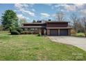 A brick home with a large front yard and an attached three car garage under a blue sky at 190 Country Dr, Statesville, NC 28625