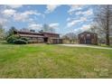 A brick home with a large front yard, detached garage, and three car garage with a blue sky at 190 Country Dr, Statesville, NC 28625