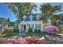 Charming two-story home with black shutters, dormers, mature landscaping and colorful flower beds at 3133 Selwyn Ave, Charlotte, NC 28209