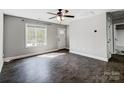 Bright, neutral living room with hardwood floors, large windows, a ceiling fan, and a white front door at 350 Belvedere Nw Dr, Concord, NC 28027