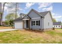 Cozy home featuring gray siding, a black roof, and well-maintained landscaping at 409 Bost St, Kannapolis, NC 28081