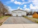 A modern white metal building featuring two roll-up doors and gravel driveway, nestled in a residential area at 5412 Carving Tree Dr, Harrisburg, NC 28075