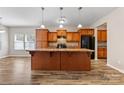 Bright kitchen with a large central island, wooden cabinets, pendant lighting, and modern flooring at 6615 Buck Horn Pl, Waxhaw, NC 28173
