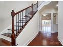 Elegant staircase with wooden steps, iron railing, and hardwood floors in a brightly lit foyer at 8513 Garden View Dr, Charlotte, NC 28277