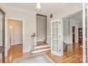 Bright foyer featuring hardwood floors, staircase, classic trim, and French doors with glass panes at 10332 Hollybrook Dr, Charlotte, NC 28277