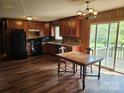 Open kitchen layout with wood cabinets, black appliances, and adjacent dining area with backyard access at 13316 E Rocky River Rd, Davidson, NC 28036