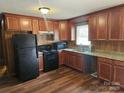 Well-lit kitchen with wooden cabinets, sleek black appliances, and durable countertops at 13316 E Rocky River Rd, Davidson, NC 28036