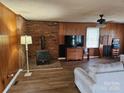Cozy living room featuring a brick fireplace, wood-paneled walls, and modern flooring at 13316 E Rocky River Rd, Davidson, NC 28036