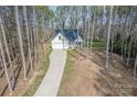 Picturesque aerial view of a home nestled in a forest with a long driveway at 13625 Buster Rd, Stanfield, NC 28163