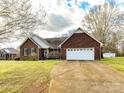 Charming brick home with an attached two-car garage, long drive, mature trees, and a well-maintained lawn at 1520 Venture Oaks Ln, Monroe, NC 28110