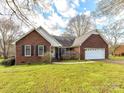 Charming brick home with an attached two-car garage, mature trees, and a well-maintained lawn at 1520 Venture Oaks Ln, Monroe, NC 28110