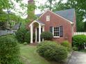 Charming brick home featuring a front entrance with white columns and lush landscaping at 2815 Glendale Rd, Charlotte, NC 28209