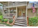 Inviting covered porch with hanging flower baskets, bench seating, and a charming entrance with an American flag at 2819 Blythe Rd, Waxhaw, NC 28173