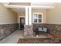 Cozy front porch area with stone accents, a comfortable bench, and a decorative front door at 3102 Arches Bluff Cir, Lancaster, SC 29720