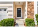 Welcoming front entrance with stone accents, a black front door, and manicured bushes at 3104 Streamhaven Dr, Indian Land, SC 29707